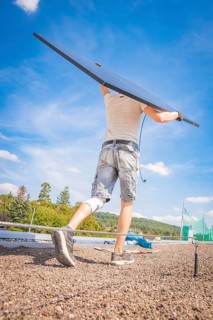 A worker lifts a solar module against the blue sky, new Park and Ride parking garage Calw Heumaden