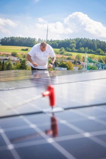 Worker checking solar modules in a landscaped area with clear skies, new park and ride Calw