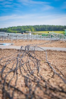 Cables run across a gravel-covered roof for solar modules under clear skies, new park and ride