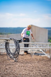 Cable against a blurred background showing workers installing a solar system, new park and ride