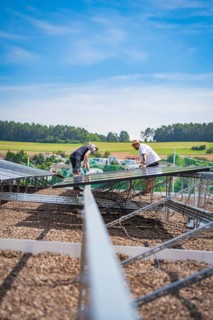 Two workers install a solar system surrounded by a quiet landscape under blue skies, new park and