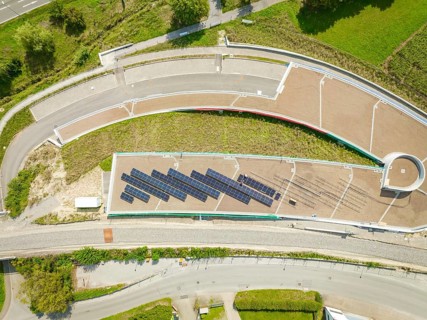 Aerial view of solar panel system on roof next to road and green area, new park and ride parking