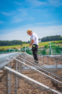 A construction worker stands on scaffolding in a rural area under blue skies, new park and ride
