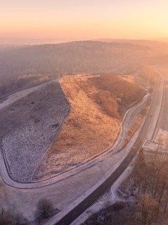 Snowy hill in sunset light with surrounding roads, old deposit, construction site for PV open space