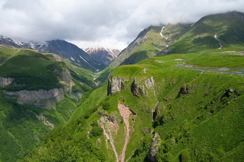 Green mountain landscape with visible road and gorges, cloudy weather, mountainous landscape