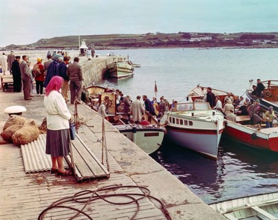 People boarding tour boats from the quayside in the harbour at Hugh Town, Isles of Scilly,