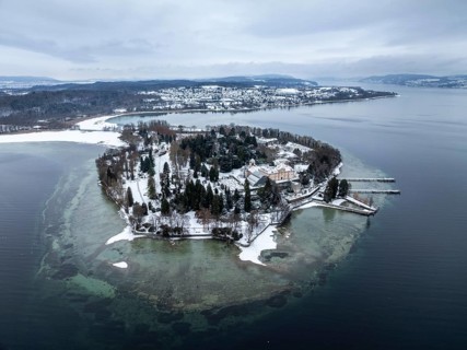 The wintry and snowy Mainau island in Lake Constance with the pier and the baroque Mainau Castle,