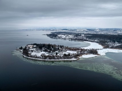 The wintry and snowy Mainau island in Lake Constance with the boat dock and the baroque Mainau