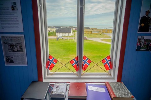 Window with Norwegian flags in the room, view of outdoor scene and books in the partisan museum in