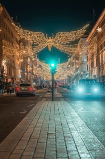 Festively illuminated street with Christmas decorations and cars at night, London, England, Great