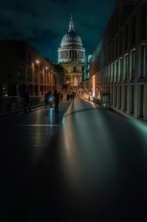 Illuminated bridge with St Paul Cathedral and city background at night, people walking, London,