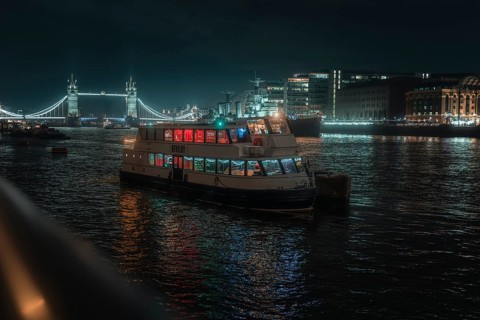 Illuminated boat on the Thames at night with Tower Bridge in the background, London, England, Great