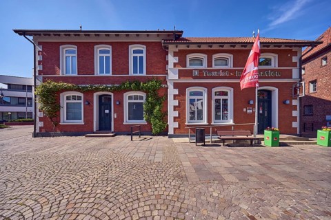 Tourist information, advertising flags on flagpoles, brick buildings, houses, bench, walkway made
