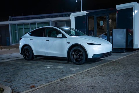 White Tesla parked at night at a charging station on grey asphalt, New Model Y Standard, Tesla
