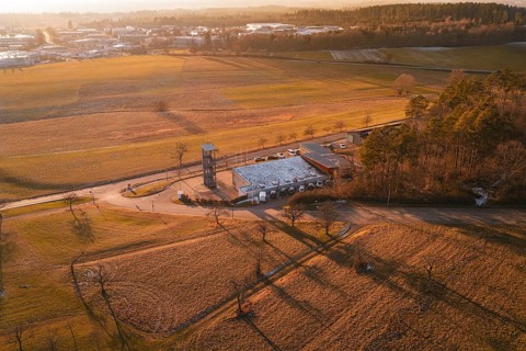 Aerial view of a landscape in evening light with fire station surrounded by fields and trees,