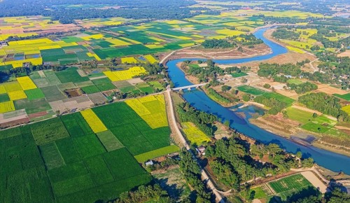 An aerial view reveals a gently curving river winding through the countryside, its silvery surface