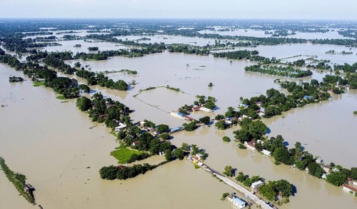 An aerial view shows widespread flooding submerging villages and farmland, with isolated homes and