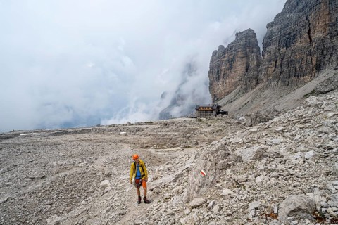 Mountaineers on a hiking trail in a rocky, cloud-covered mountain landscape while descending to