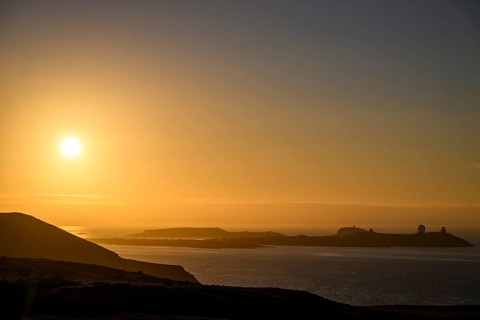 Midnight sun on Mount Domen in the background the city of Vardø, sea at sunset with golden sky and