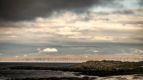 Atmospheric coastal landscape with cloudy sky over a vast sea on the coastal road in the north of