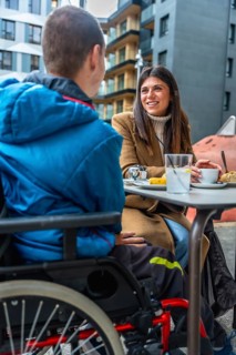 Woman and boy with disabilities enjoying a conversation together while sitting at an outdoor cafe