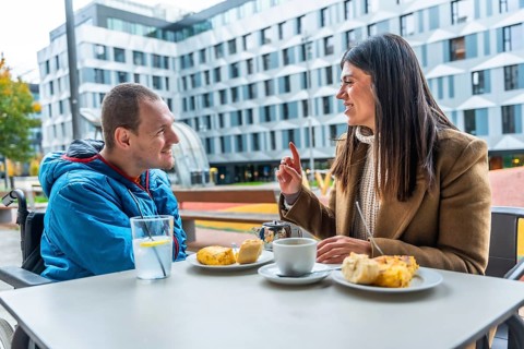 Man with a disability in a wheelchair discussing and smiling with his female social worker over