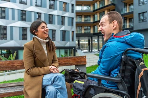 Young woman and man with a physical disability in a wheelchair sharing a joyful moment and smiling