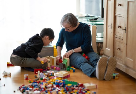 Elderly woman, grandma, boy, 6 years, grandson, glasses, multi-ethnic, playing together with Lego,