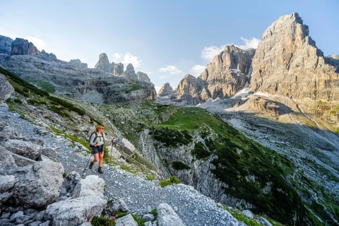 Female mountaineer hiking on a hiking trail in front of picturesque mountain scenery in the