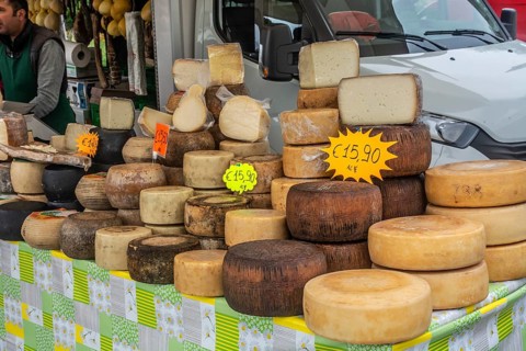 Various cheeses for sale on a table at market in Alghero, Sardinia, Italy