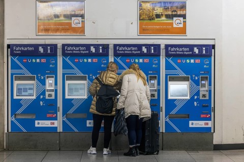 Ticket vending machine at Stuttgart Airport with travelers buying a public transport ticket.