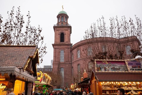 December 22, 2025, people strolling past festive wooden stalls at the Christmas market near St.