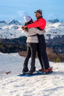 Happy couple embracing each other while snowshoeing on a snowy mountain landscape, enjoying a