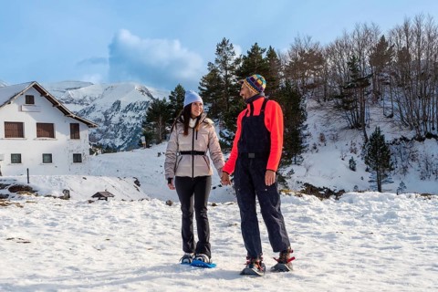 Happy couple holding hands while snowshoeing on a sunny winter day, enjoying active leisure time in