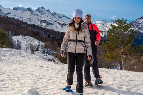 Couple snowshoeing side by side through fresh deep snow in the pyrenees on a sunny winter day,