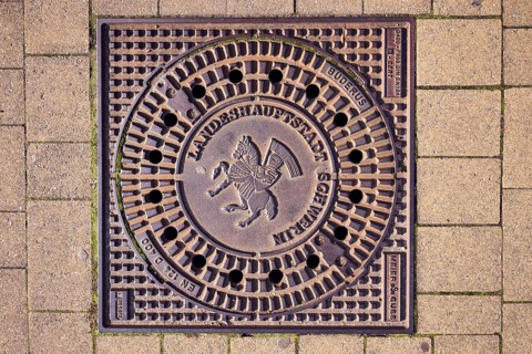 Manhole cover, city coat of arms, concrete paving stone walkway, Schwerin, state capital,