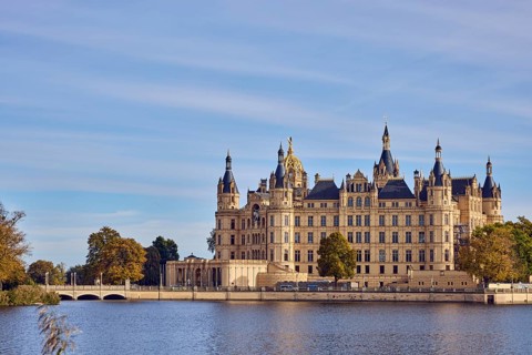 Castle, Burgsee lake, trees, bushes, car bridge and footbridge, water surface with small waves,