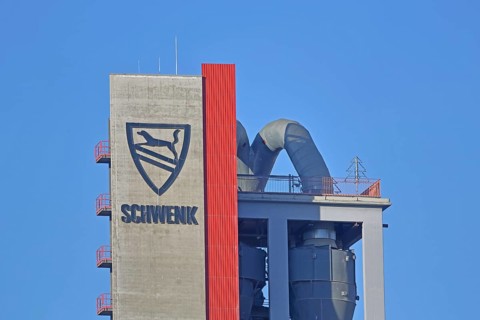 Silo with inscription and emblem of Zementfabrik Schwenk Manufacture of cement, tower with pipes,
