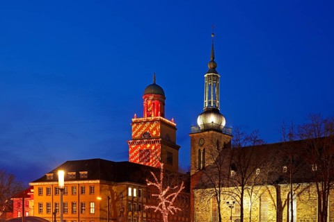 The Christmassy illuminated town hall tower and the illuminated church tower of St. John's Church