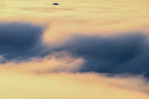 View from Mount Domen. Thick sea fog hangs over the Barents Sea and the midnight sun shines in an