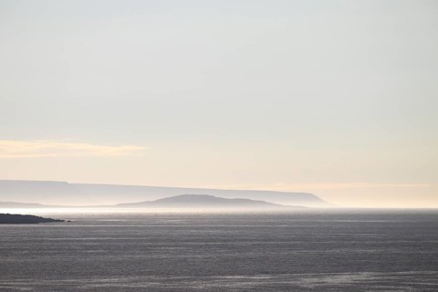 Vardø, Finnmark, Norway, Atmospheric seascape with soft lighting at sunset and silhouetted island