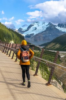 Hiker walking along the glass floored skywalk enjoying the scenic view of the athabasca glacier and