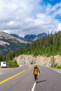 Female tourist walking on the iconic icefields parkway in the canadian rockies, enjoying