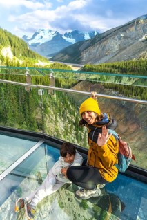 Mother and child waving from the glass platform of the glacier skywalk, enjoying the stunning
