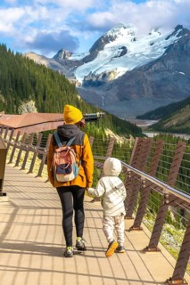 Mother and child walking on the glass floored skywalk, taking in stunning views of athabasca