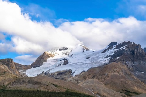 Athabasca glacier is melting under a cloudy sky, showing the effects of climate change on the