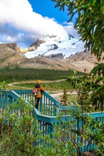 Tourist with backpack standing on wooden turquoise viewpoint is admiring stunning view of athabasca