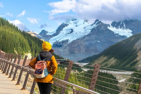Tourist admiring athabasca glacier from the skywalk in jasper national park, experiencing the