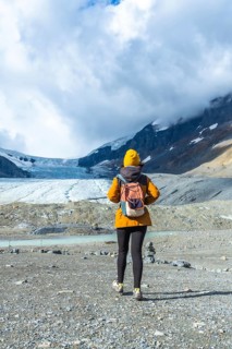Hiker walking on the rocky terrain towards the athabasca glacier in jasper national park, alberta,