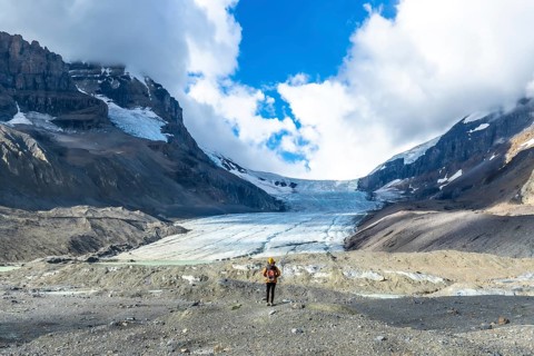 Hiker standing in front of the impressive athabasca glacier in jasper national park, canadian
